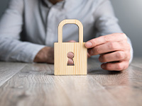 Man holding wooden cut-out of a padlock.